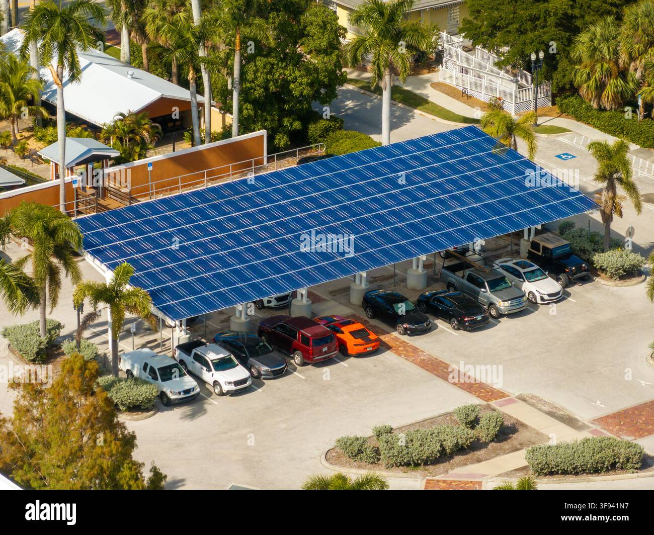Tecnologia di generazione di energia solare integrata nelle infrastrutture urbane. Pannelli fotovoltaici installati come tetto ombreggiato sul parcheggio con auto parcheggiate Foto Stock
