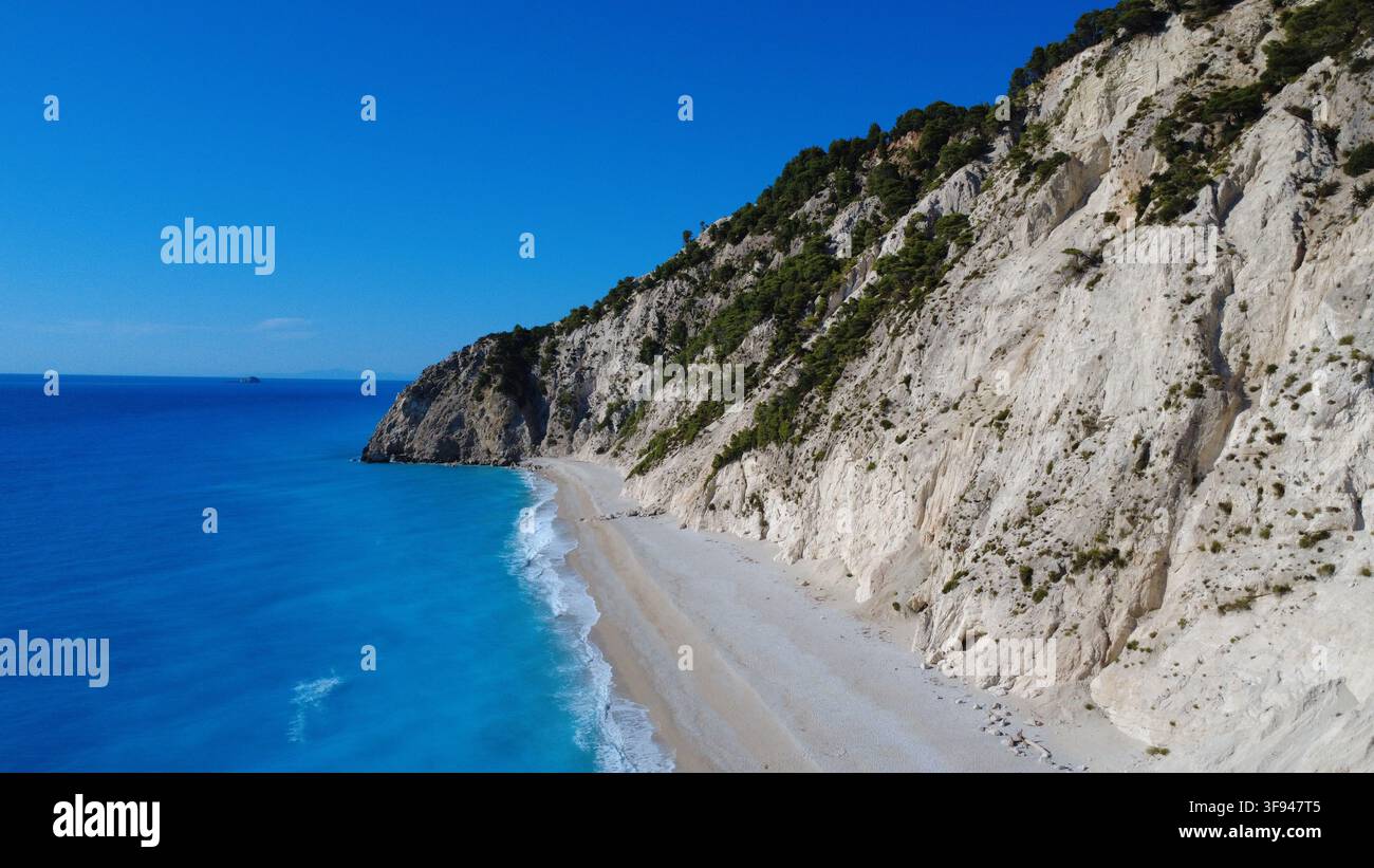 Splendida veduta aerea di una spiaggia isolata con acque turchesi che incontrano drammatiche scogliere di calcare bianco ricoperte di vegetazione verde. Foto Stock