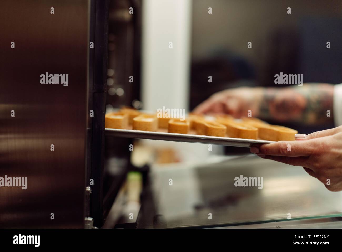 Il pasticcere posa una teglia con tartine nel forno Foto Stock