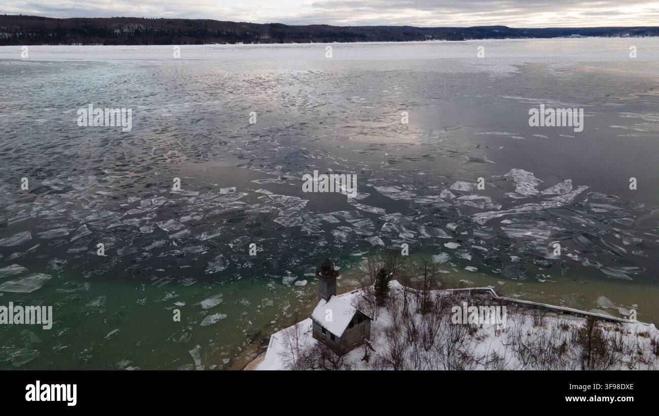 Vista aerea del faro di Grand Island circondato da alberi innevati e dalle acque ghiacciate del Lago Superiore a Munising, Michigan, Stati Uniti. Foto Stock