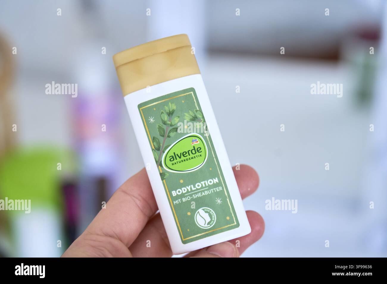 Flacone di lozione per il corpo bianca con burro di karité organico tenuto in mano, etichetta di cosmetici naturali alverde, lozione per il corpo con burro di karité organico, Alverde, di DM Foto Stock