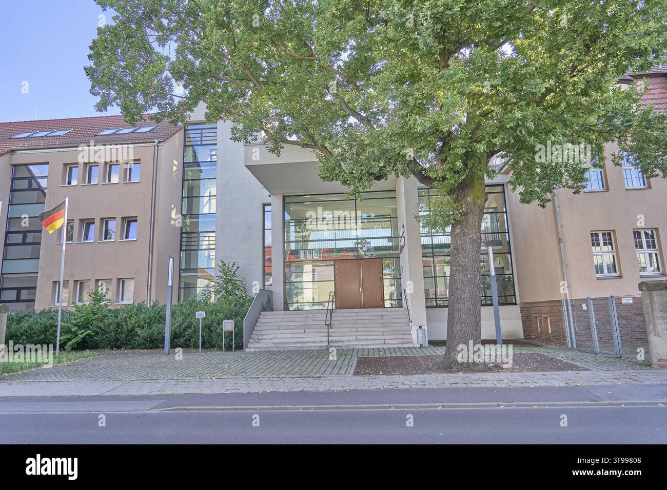 Edifici moderni con facciata in vetro e asta della bandiera tedesca davanti a un grande albero, scuola secondaria Marie Gerike in Gerikestrasse 26A, 39340 Haldenslebe Foto Stock