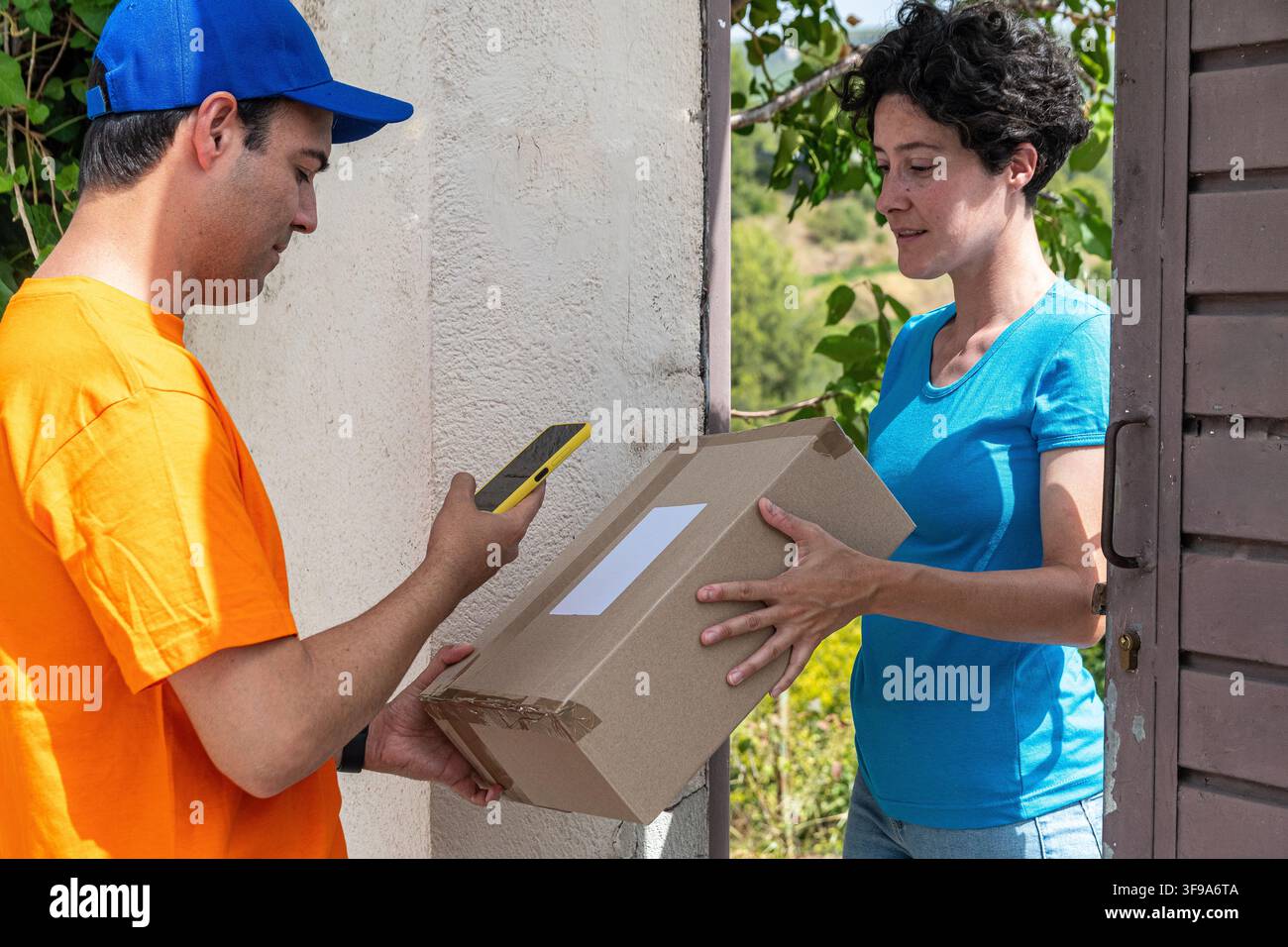 Corriere che consegna un pacco a una donna che scansiona un codice a barre Foto Stock