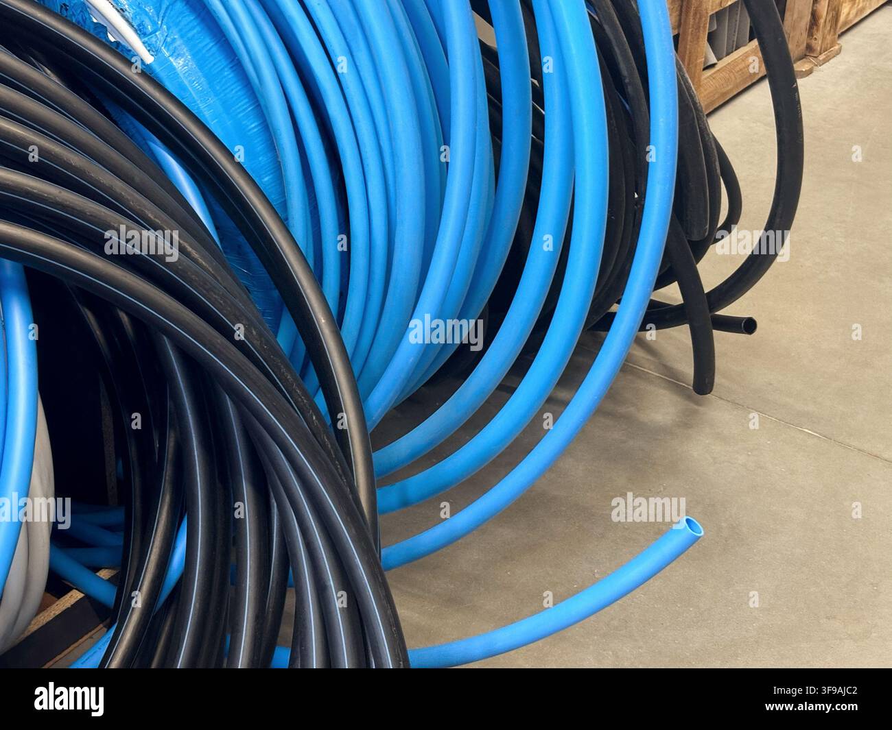 Bobine di tubi e manicotti in plastica nera e blu sugli scaffali nel reparto ferramenta per idraulica. Foto di alta qualità Foto Stock