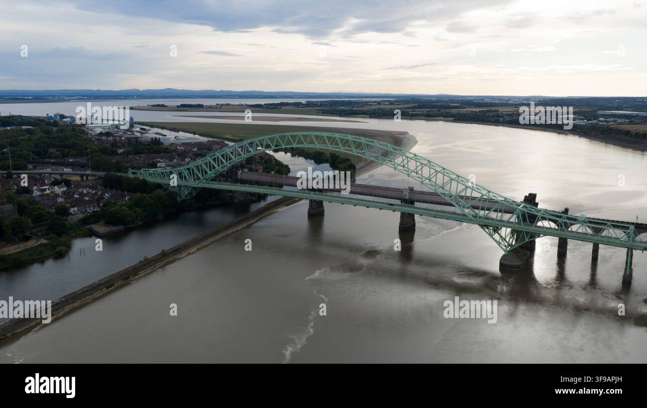 Vista aerea del ponte del Giubileo d'Argento che attraversa il fiume Mersey con dintorni urbani e acque calme a Runcorn, Regno Unito. Foto Stock