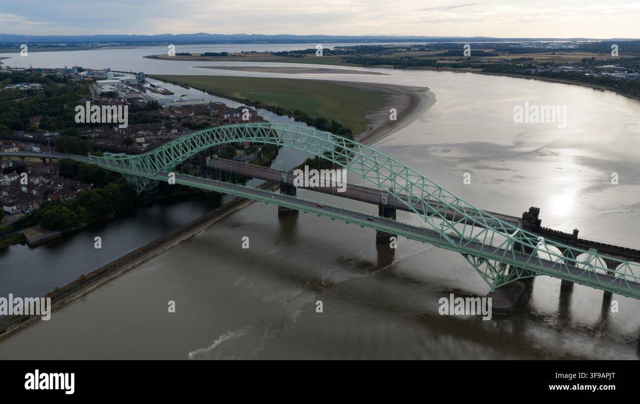 Vista aerea del ponte del Giubileo d'Argento che attraversa il fiume Mersey con dintorni urbani e acque calme a Runcorn, Regno Unito. Foto Stock