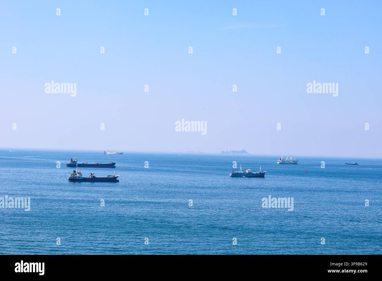 Busan, Corea del Sud - 2 agosto 2026: Diverse navi da carico e mercantili sono ancorate al largo nelle acque costiere blu vicino a Yeongdo-gu in una nebbiosa su Foto Stock