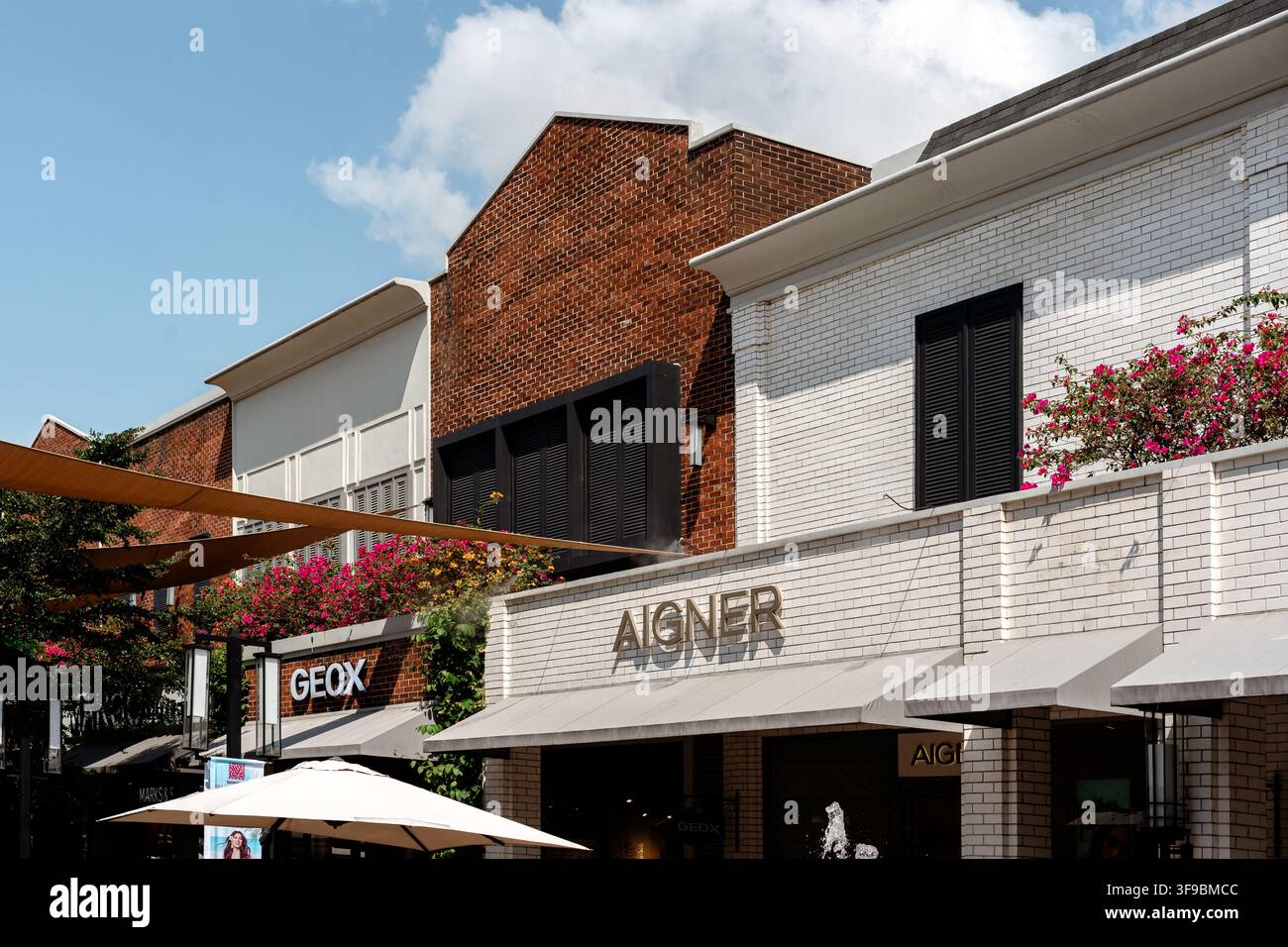 REGNO DI BEKASI, INDONESIA - 1 LUGLIO 2025: Una vista a livello degli occhi di una strada commerciale all'aperto con vetrine di negozi al dettaglio delle marche Geox e Aigner. Foto Stock