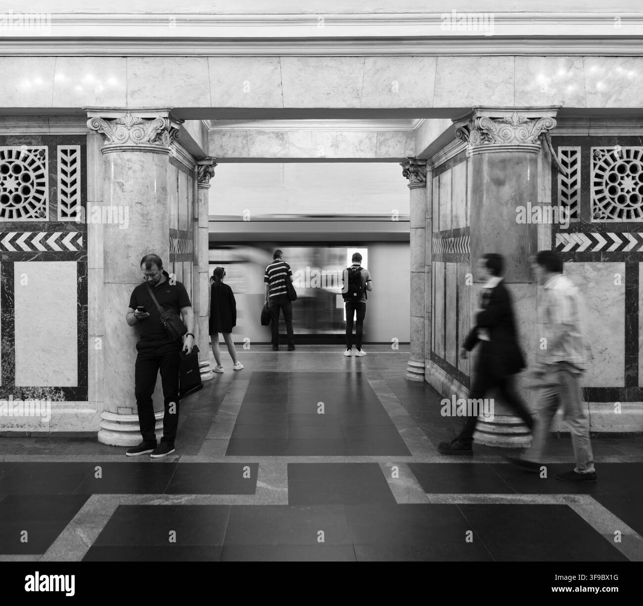 Pendolari in sfocatura di movimento attraversano l'elegante palazzo sotterraneo di una storica stazione della metropolitana di Mosca. B&N. Foto Stock