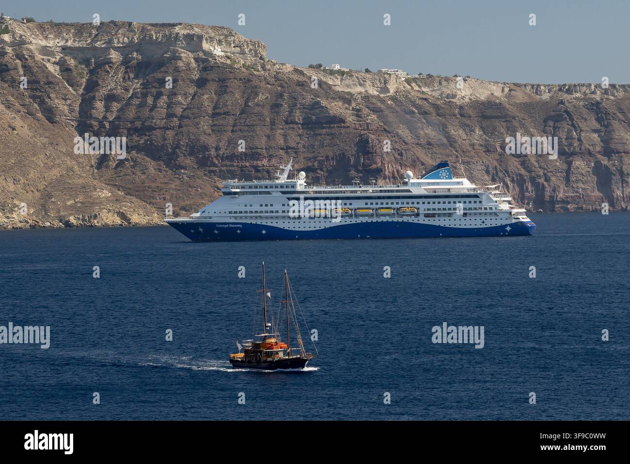 La Celestyal Discovery all'ingresso nella caldera di Santorini, davanti una piccola barca a vela GRC, tema viaggi, Thira - Santorini, 06.08.2 Foto Stock