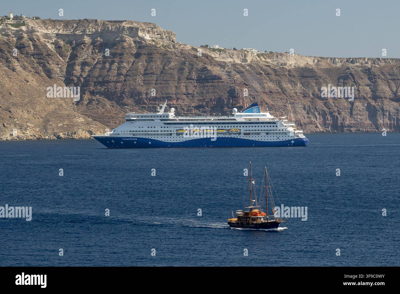 La Celestyal Discovery all'ingresso nella caldera di Santorini, davanti una piccola barca a vela GRC, tema viaggi, Thira - Santorini, 06.08.2 Foto Stock