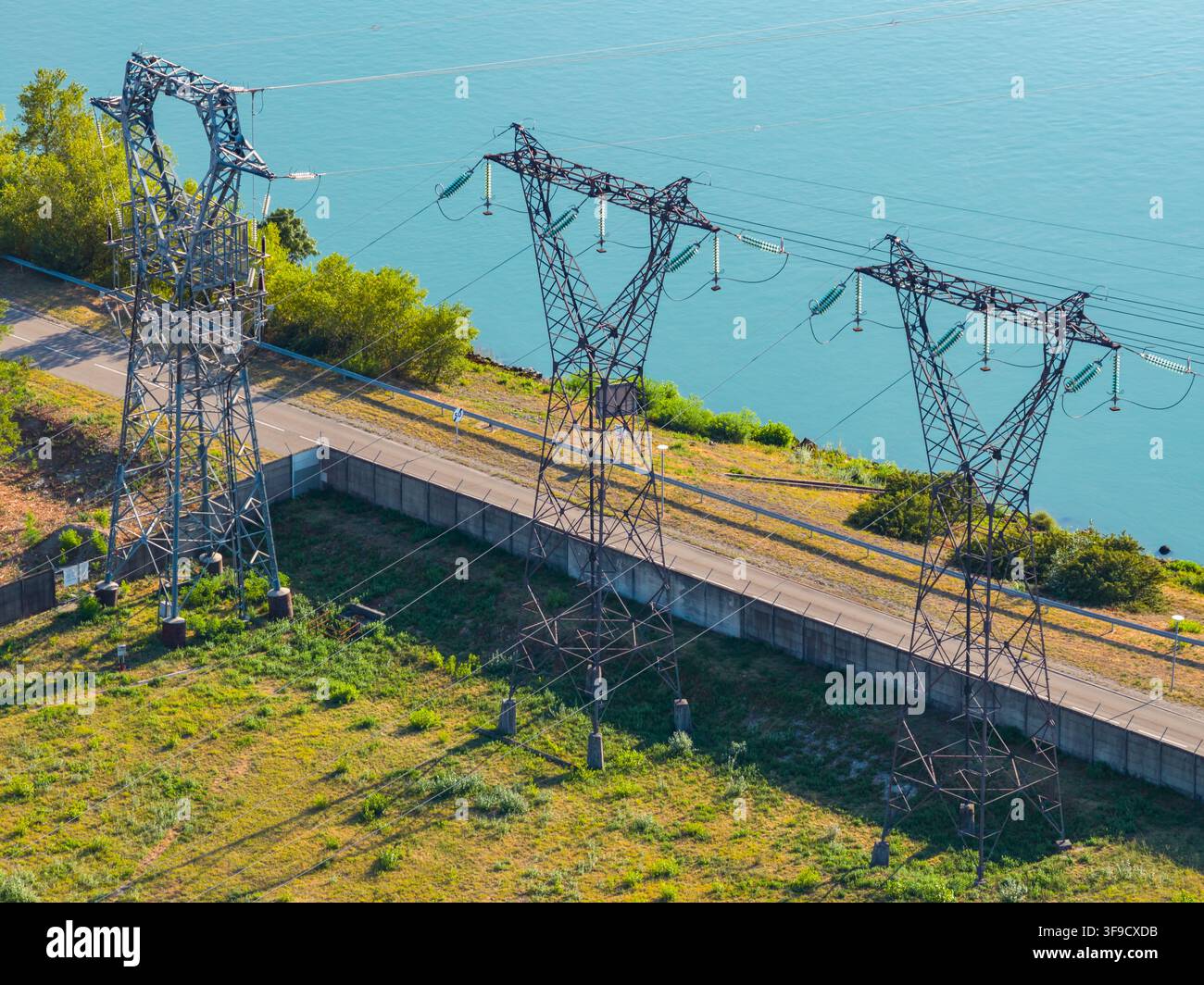 Veduta aerea di tralicci di trasmissione ad alta tensione e linee elettriche vicino a un fiume a Saulce-sur-Rhone, Alvernia-Rodano-Alpi, Francia. Foto Stock