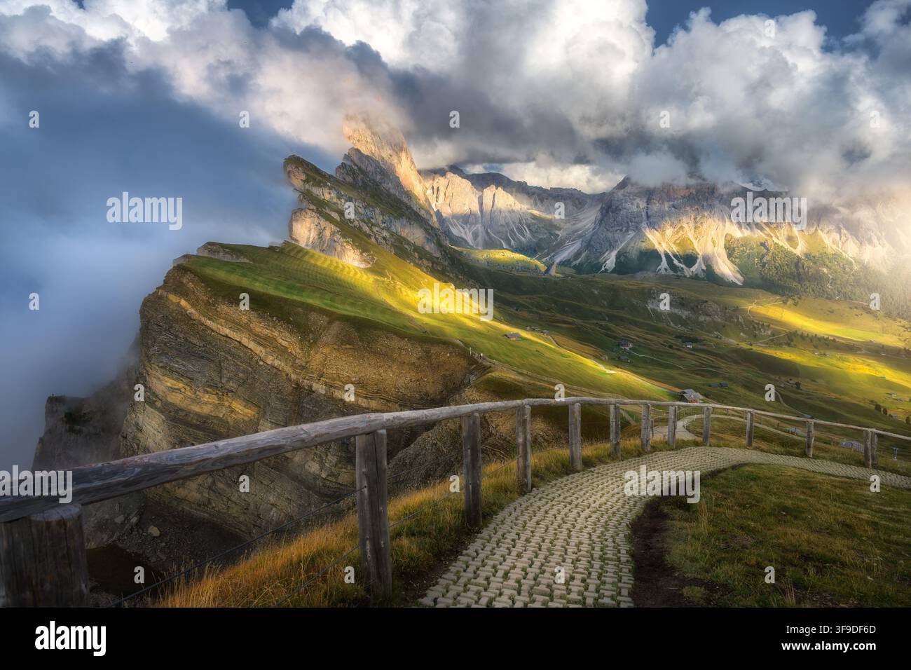Somma del monte Seceda tra le nuvole con sentiero escursionistico e recinzione di legno Foto Stock