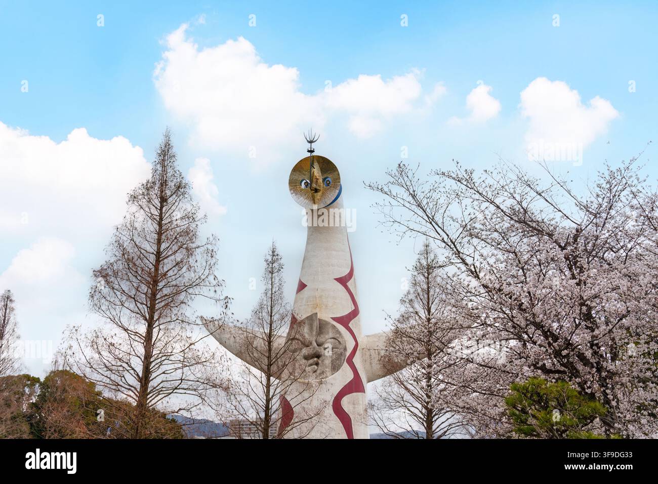 La famosa Torre del Sole si erge sotto un cielo azzurro circondata da un giardino di ciliegi in fiore nel Parco Commemorativo Expo 70 di Osaka, Giappone Foto Stock