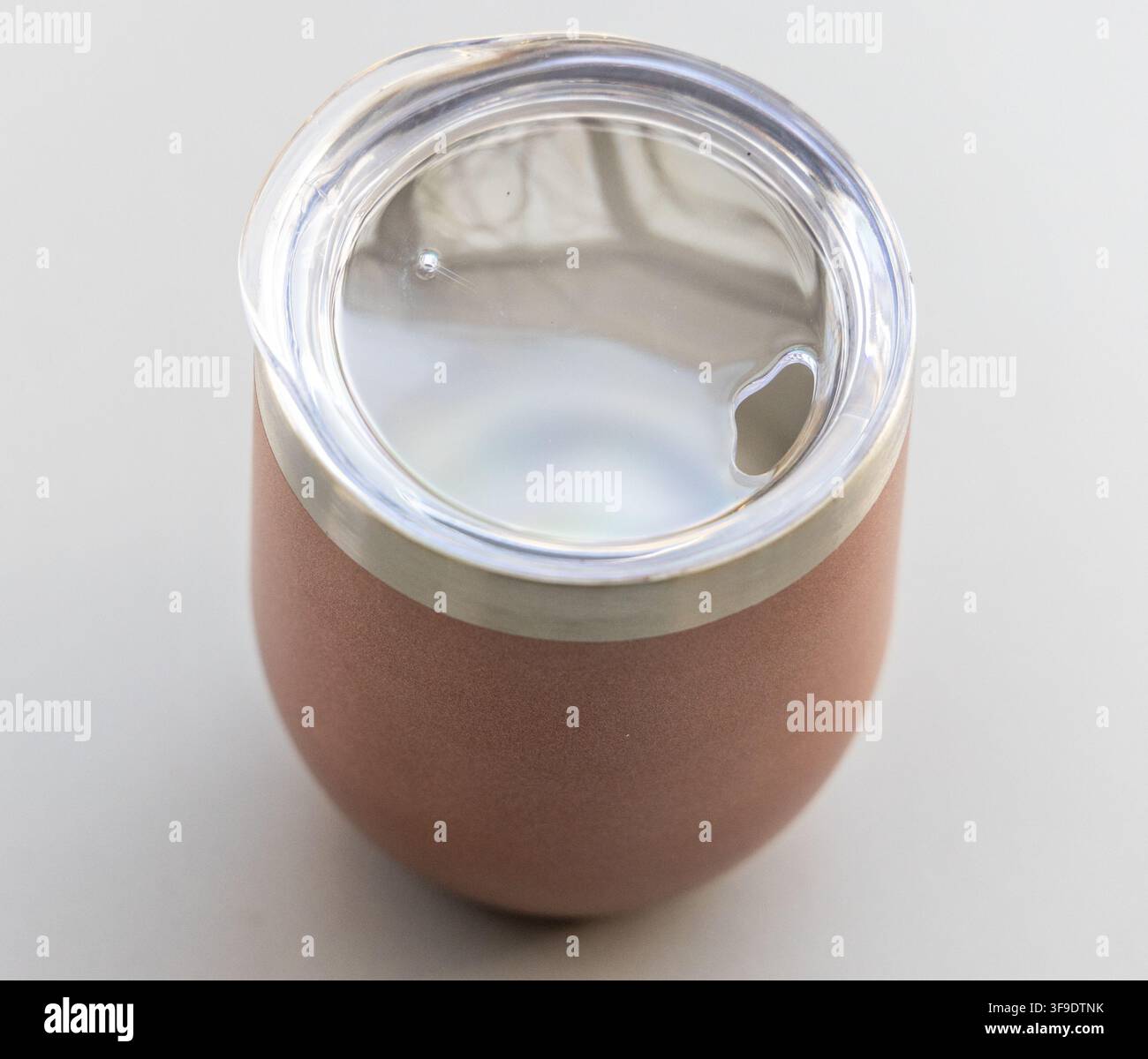 Viene mostrato un elegante tumbler isolato in oro rosa con coperchio trasparente Foto Stock