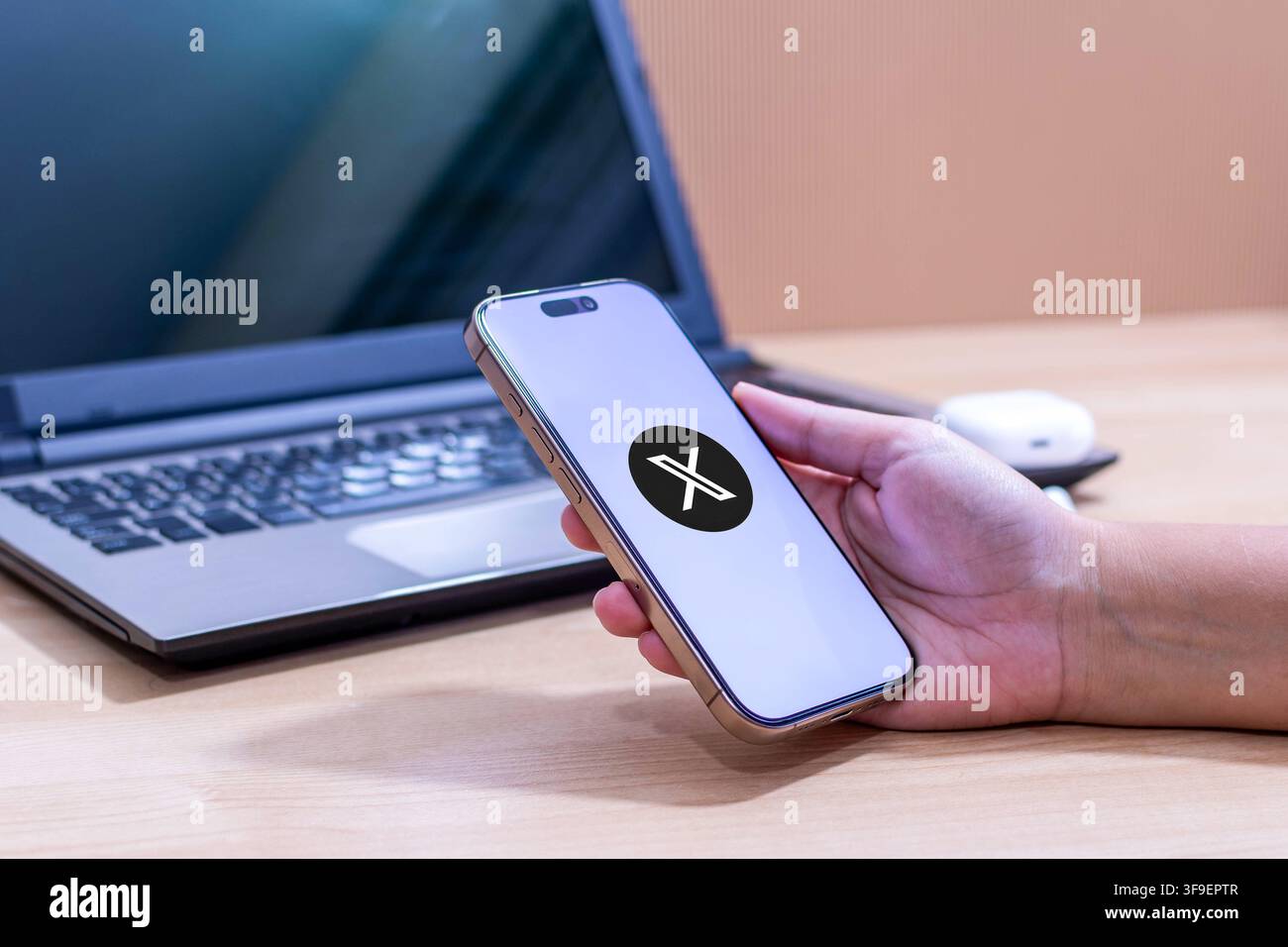 Mano che tiene un iPhone con il logo dell'app X. Foto Stock