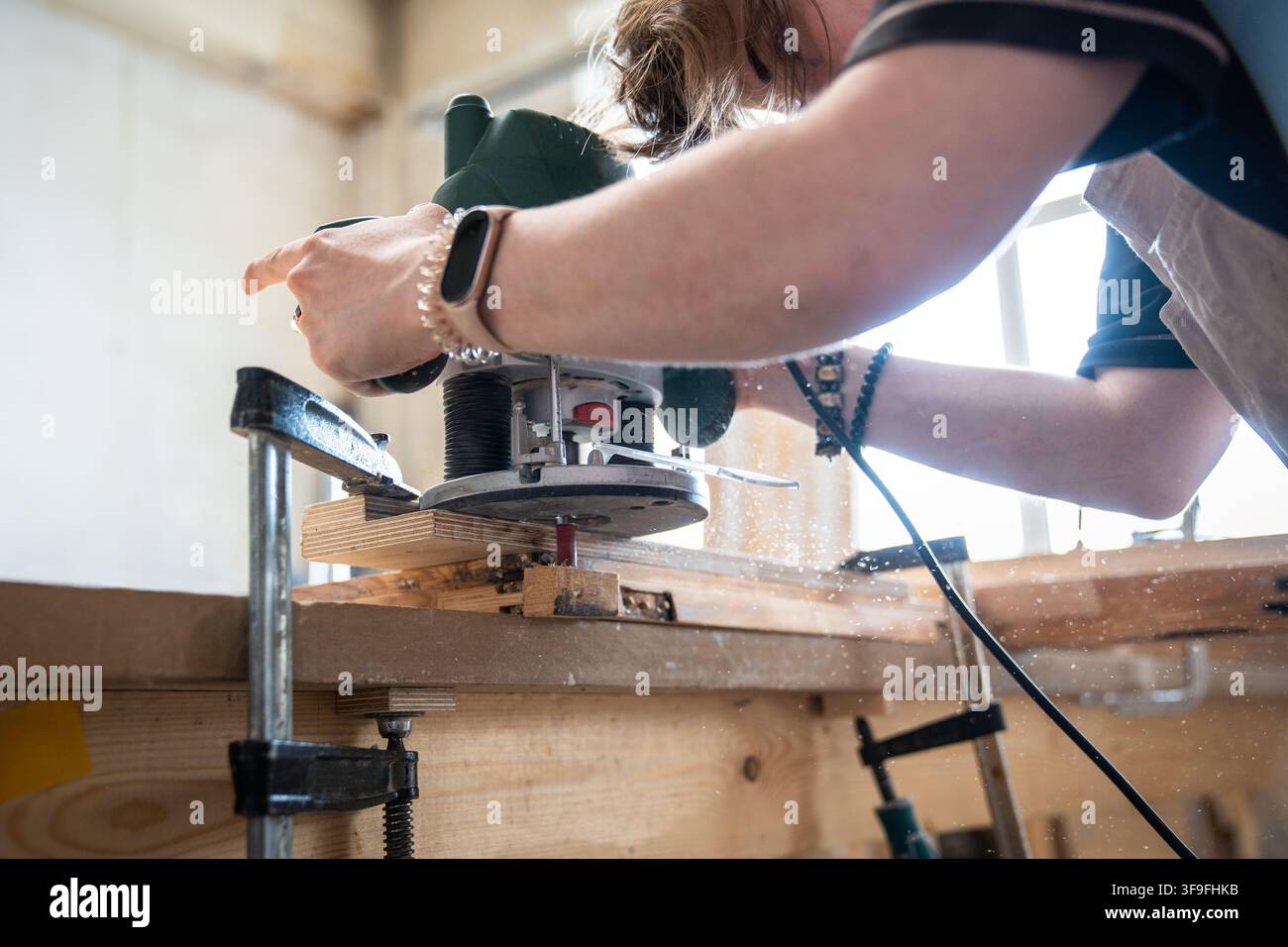 Falegnama esperta che lavora con una fresatrice elettrica per legno sul posto di lavoro in un laboratorio di falegnameria Foto Stock