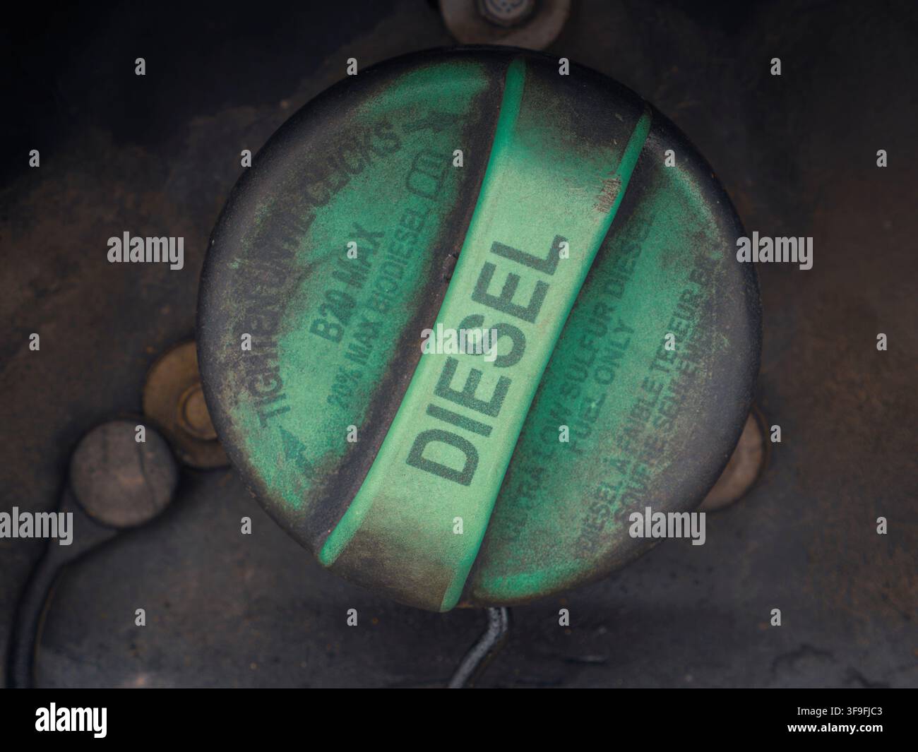 Primo piano di un tappo del serbatoio di carburante diesel verde e sporco etichettato con istruzioni su un veicolo pesante all'aperto Foto Stock