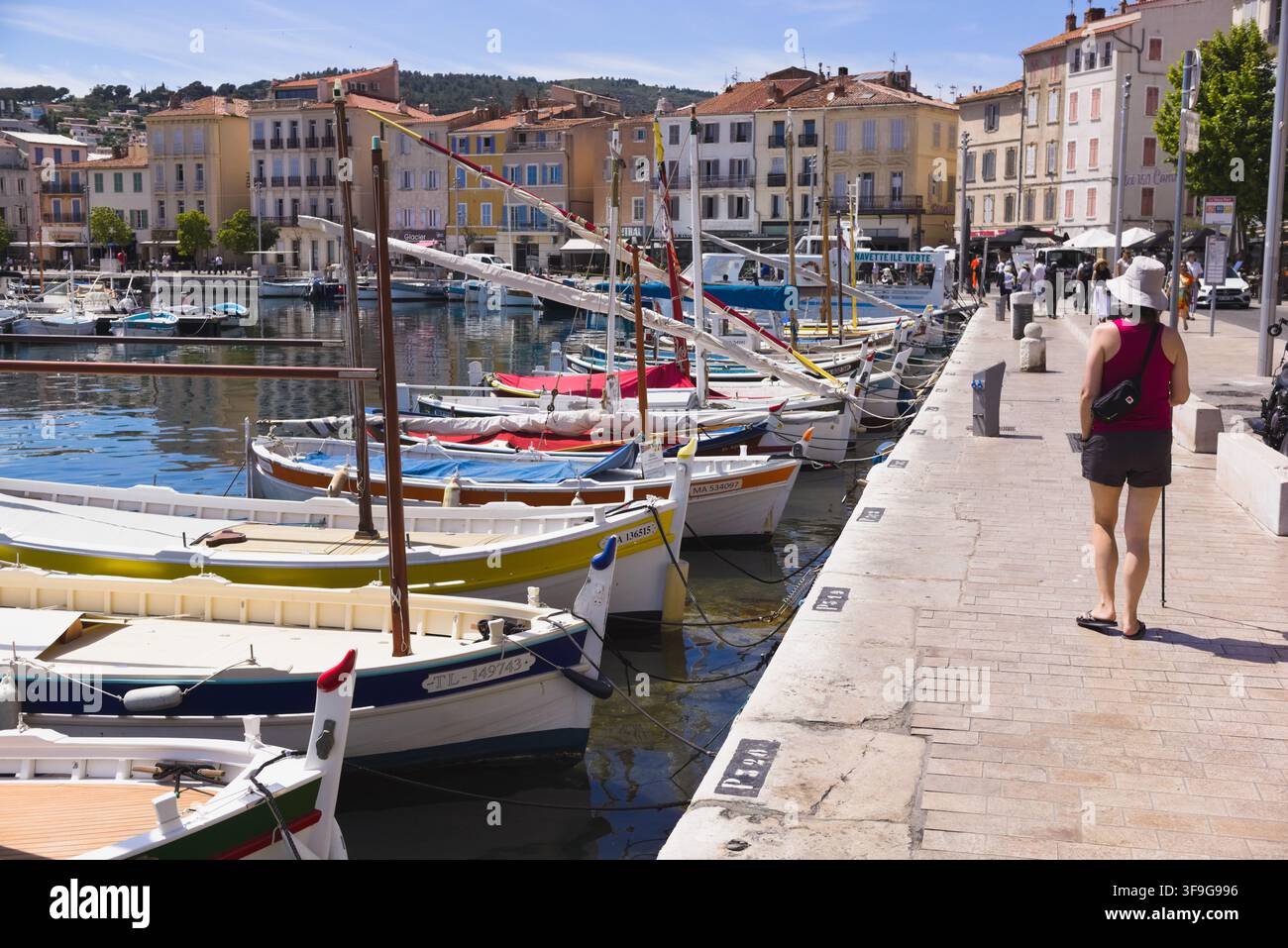 Un turista che cammina lungo il molo del porto lungomare fiancheggiato da barche tradizionali a La Ciotat, Costa Azzurra, Francia. Foto Stock