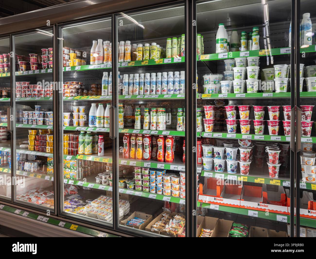 Kyiv, Ucraina – 14 marzo 2026: Varie bottiglie di latte e vasetti di yogurt esposti sugli scaffali freddi del frigorifero di un supermercato, che mostrano un ambiente di vendita al dettaglio ordinato Foto Stock