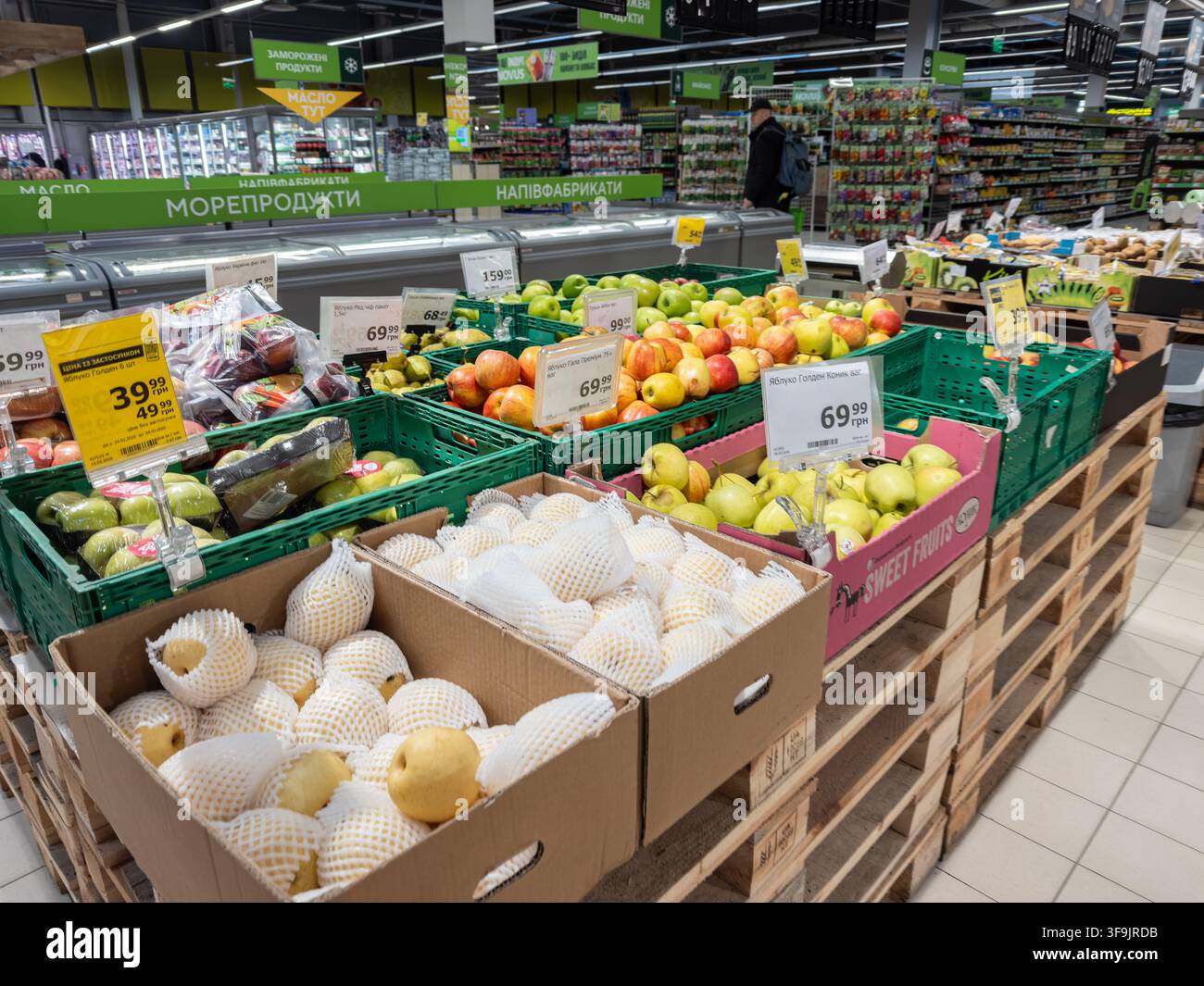Kyiv, Ucraina – 14 marzo 2026: Varietà di frutta fresca assortita confezionata in manicotti protettivi a rete all'interno di scatole di cartone in un negozio di alimentari, rappresentano Foto Stock