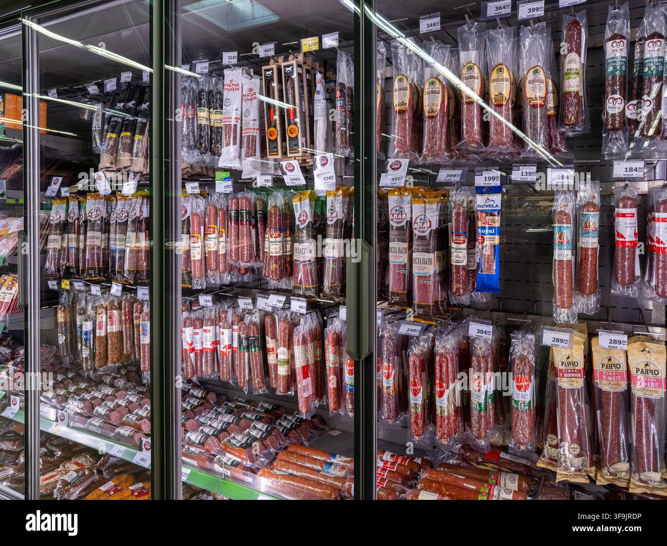 Kiev, Ucraina - 14 marzo 2026: Vari prodotti carnei confezionati in involucri di plastica trasparenti riposti sugli scaffali del congelatore di un supermercato, che riflettono la fo moderna Foto Stock