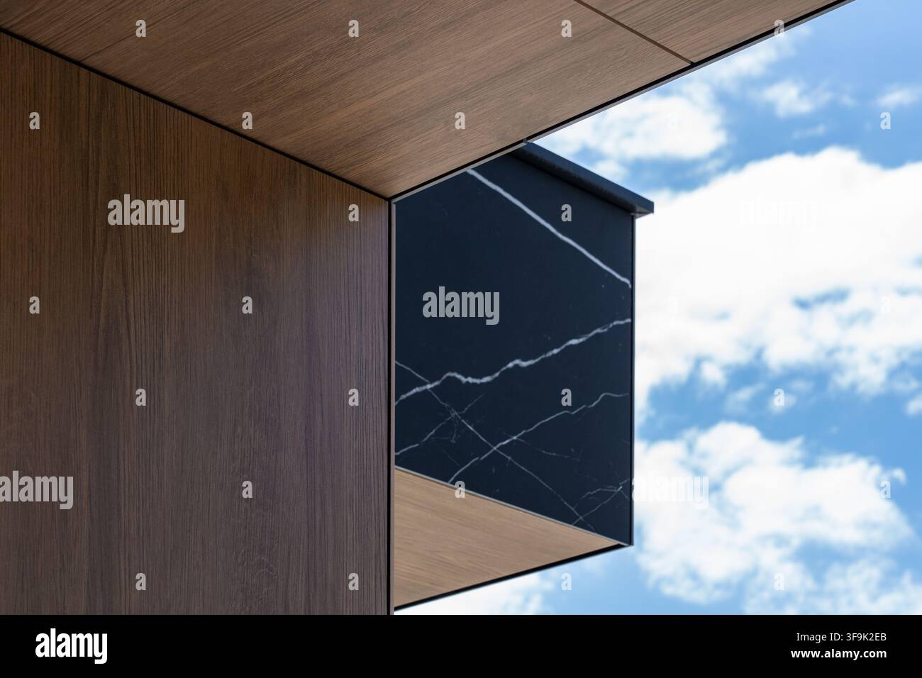 Dettaglio del cornicione di architettura moderna che combina marmo venato e piastrella in legno scuro, contrasto di materiali della facciata della casa di lusso Foto Stock