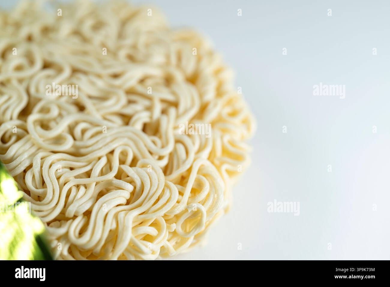 Macro di una torta di noodle istantanei crudi su tavolo bianco Il concetto di cibo trasformato e cena veloce Foto Stock