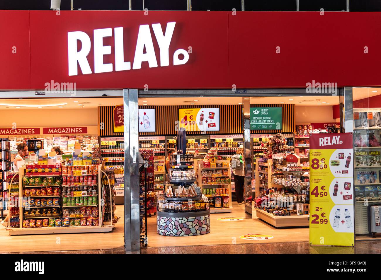 La vetrina di un negozio di giornali e generi di prima necessità Relay, che espone riviste, snack e souvenir, all'aeroporto di Barcellona. Foto Stock