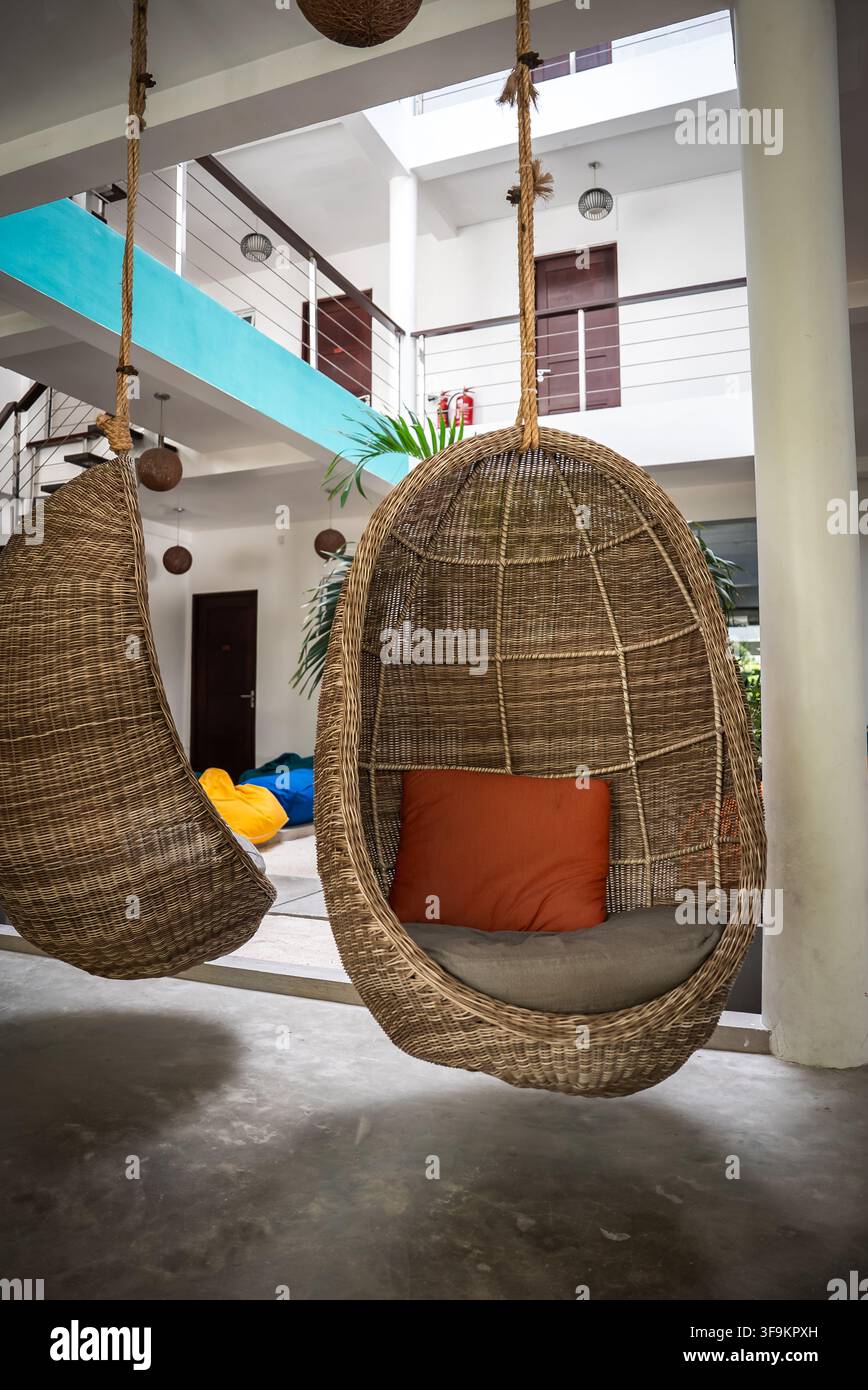 Sedie a uovo in vimini sospese in una moderna hall d'albergo alle Maldive Foto Stock