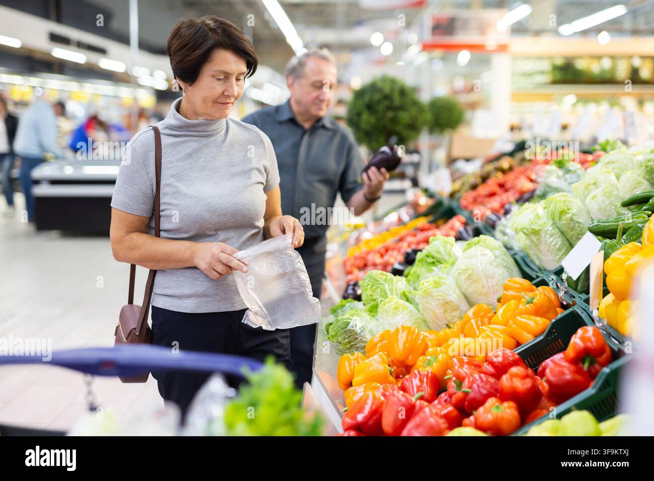 la donna anziana sceglie il pepe nel reparto di verdura e frutta Foto Stock