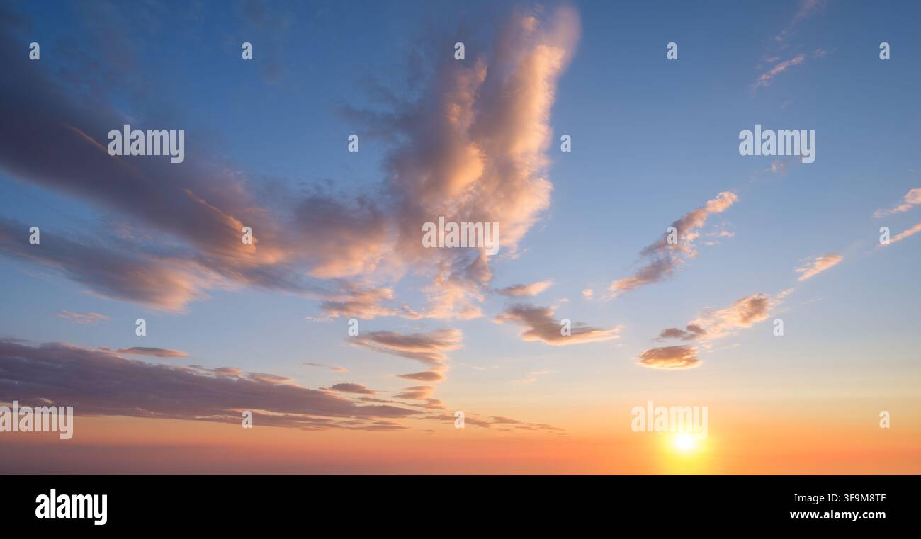Un cielo drammatico al tramonto mette in mostra colori vivaci e nuvole soffici, creando un'atmosfera serena mentre la giornata volge al termine. Foto Stock