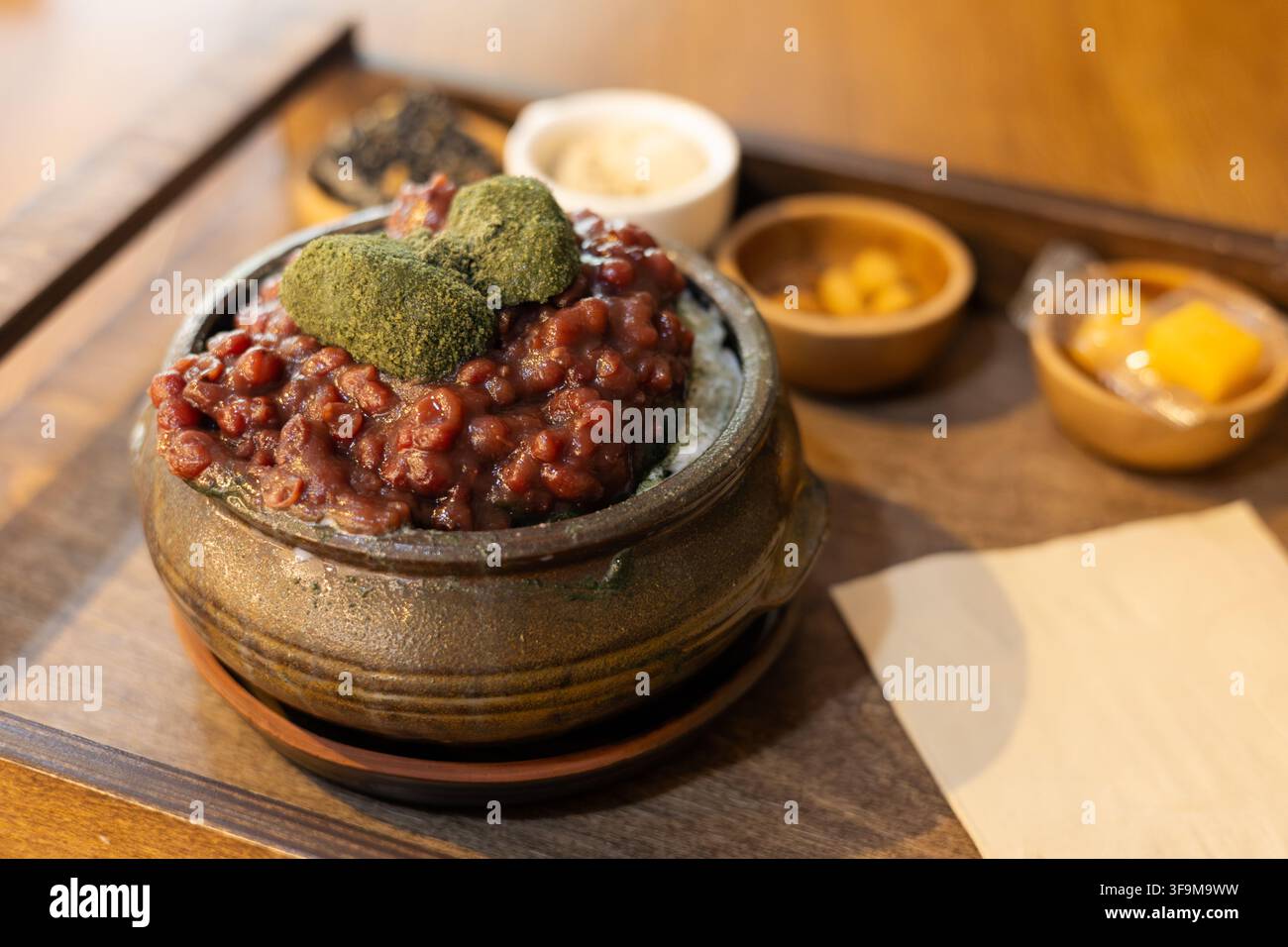 Un dessert tradizionale coreano di ghiaccio raschiato guarnito con fagioli rossi dolci e tortini di riso all'artemisia verde. Foto Stock