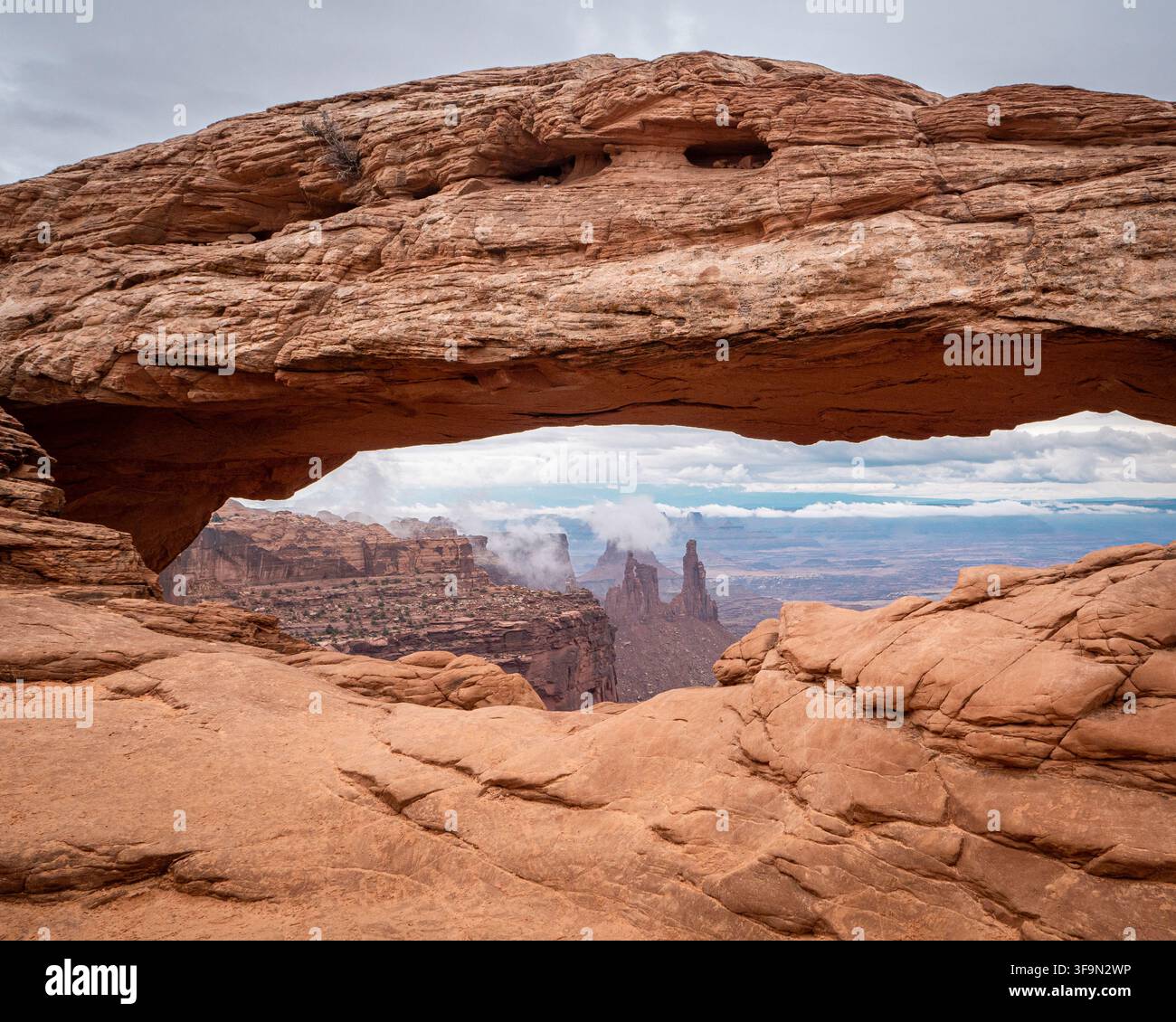 Mesa Arch incornicia le iconiche guglie del canyon del parco nazionale di Canyonlands dopo una tempesta del deserto. Foto Stock