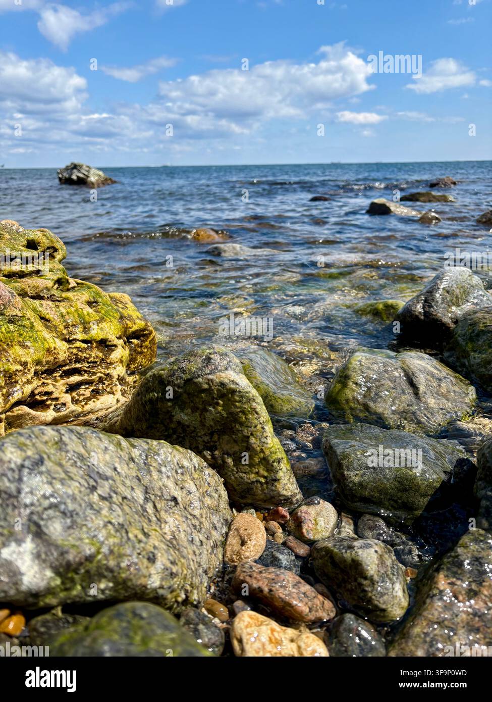 Grandi rocce costiere contro il profondo mare blu e il cielo nuvoloso Foto Stock
