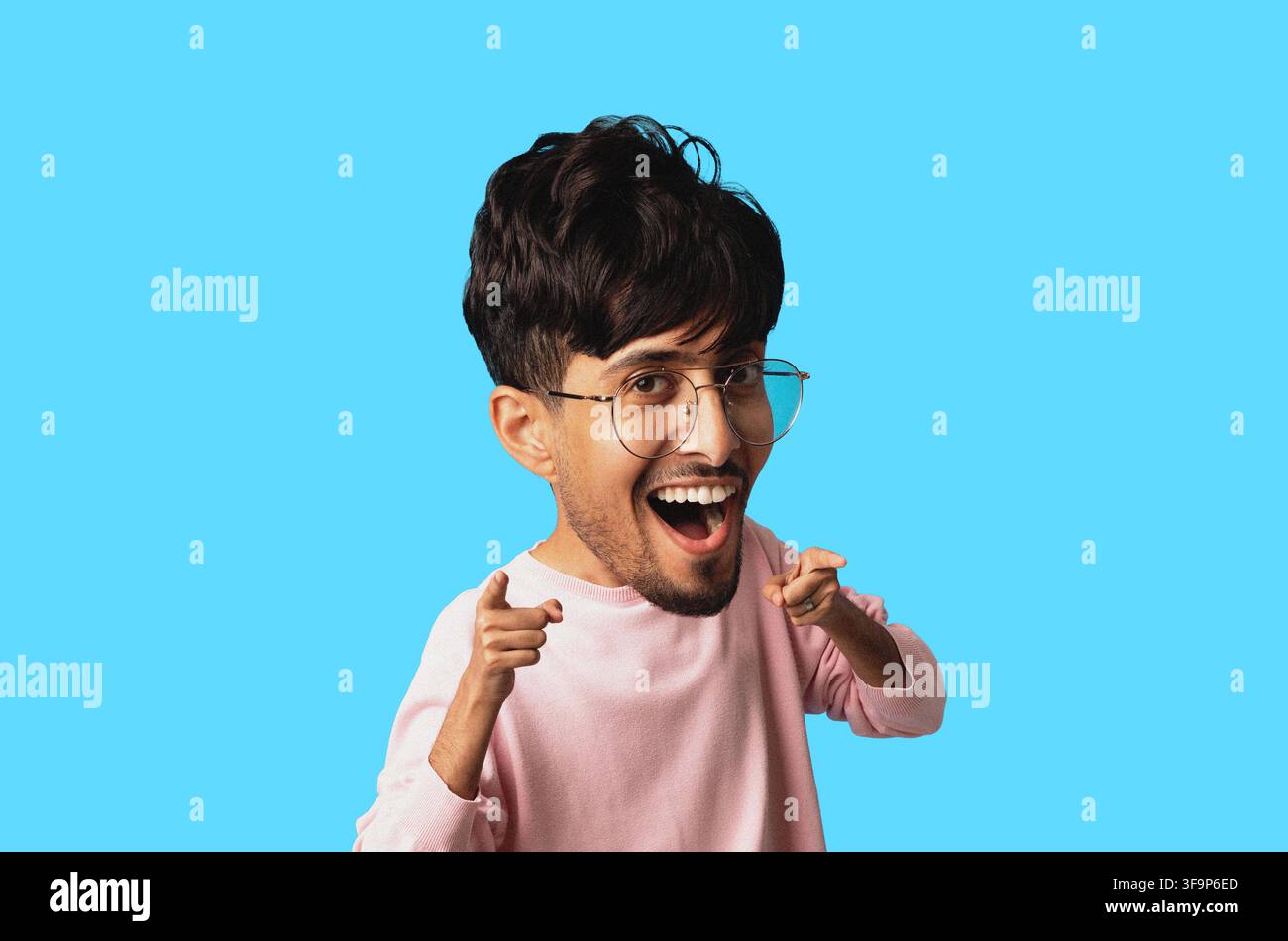 Giovane uomo felice con gli occhiali che indica la fotocamera, sorridendo, sfondo blu, concetto di stile di vita Foto Stock