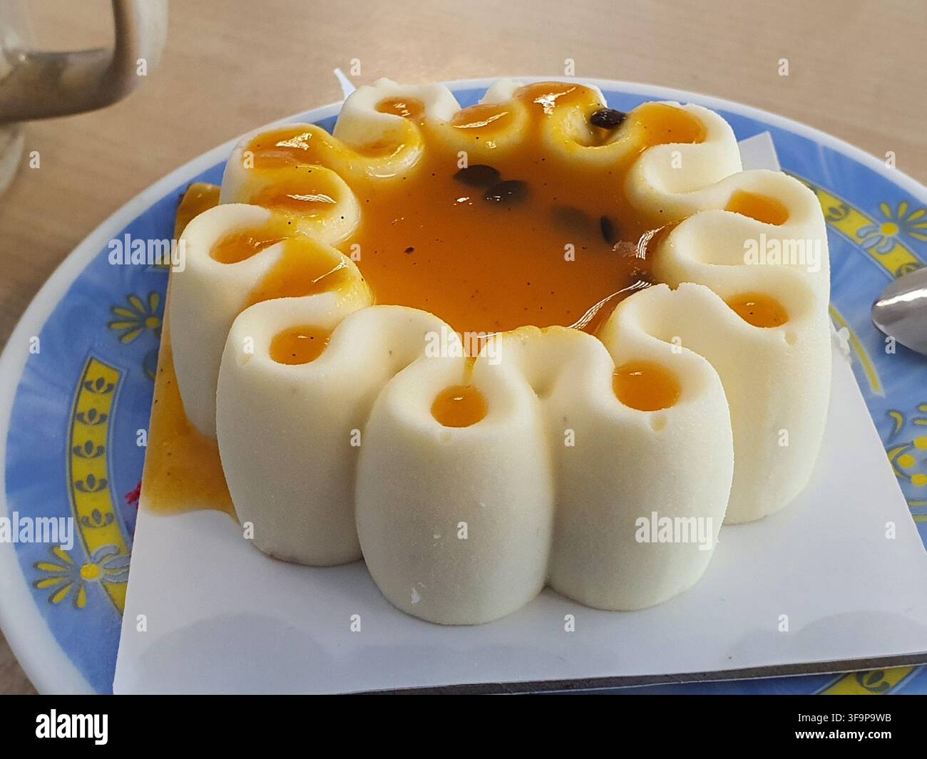 Una foto ravvicinata di un dessert bianco rotondo ed elegante con un design distintivo del bordo a forma di fiore o a cavetto, che presenta più petali arrotondati Foto Stock