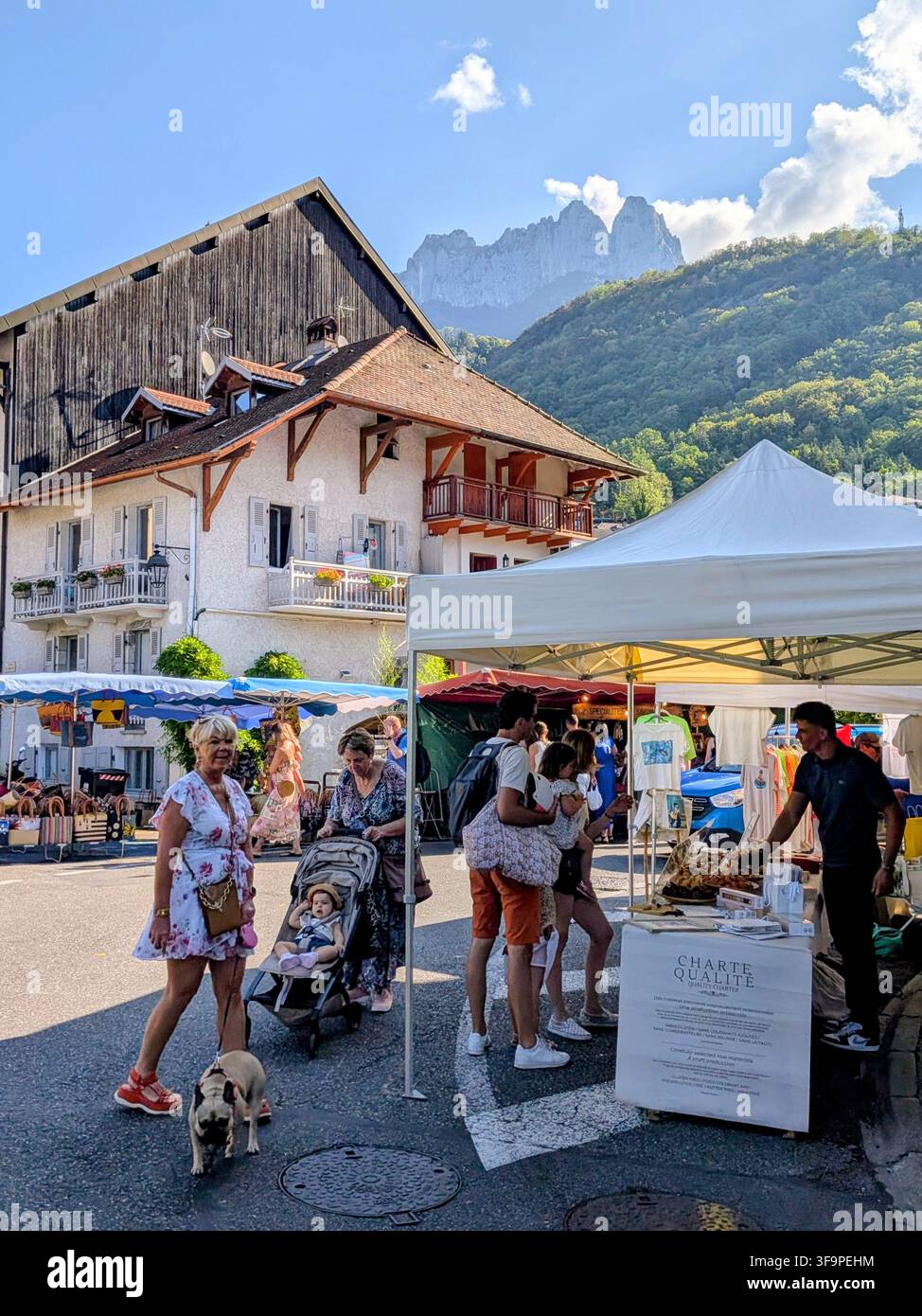 Persone che esplorano il mercato locale dei contadini con montagne sullo sfondo Foto Stock