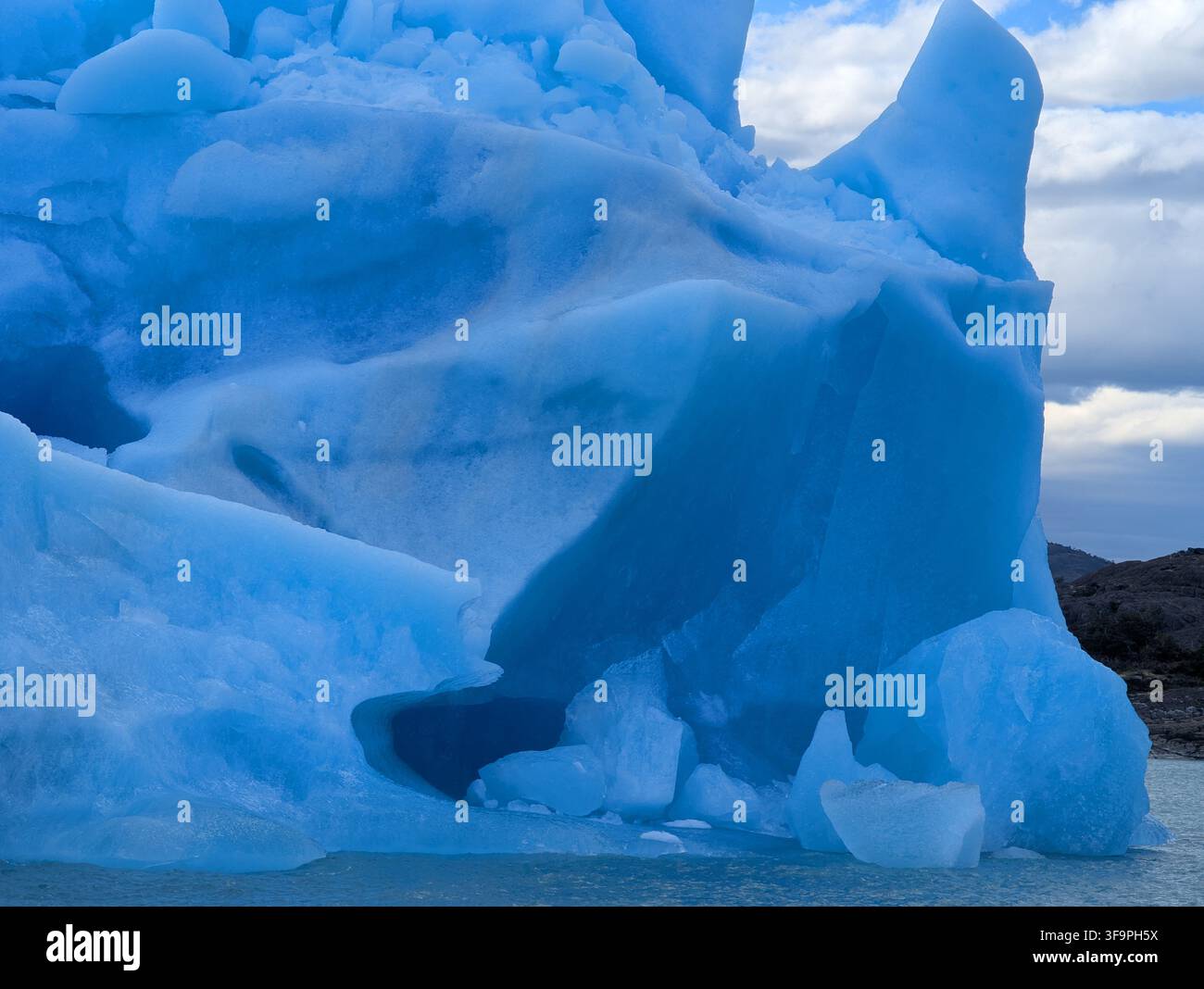Estremo primo piano di ghiaccio glaciale scolpito che rivela una profonda crepa blu, strati compressi e texture ghiacciate ruvide su un iceberg nel Canal Upsala, Arg Foto Stock