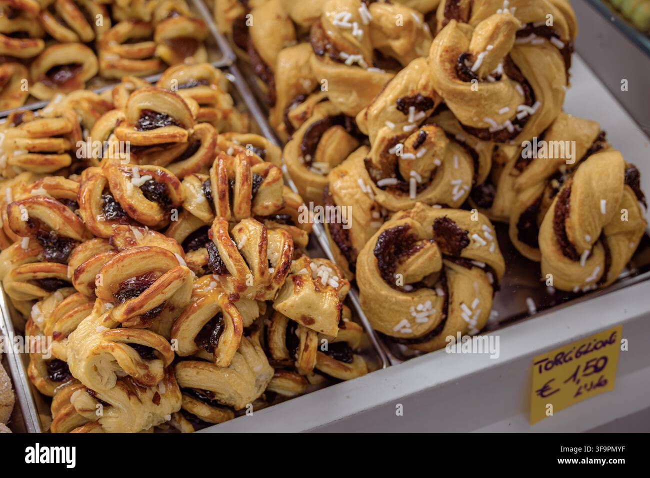 Rotoli di pasta torciglione gonfi e attorcigliati ripieni di crema al cioccolato e nocciole e cosparsi di zucchero perlato in una panetteria a Sanremo, Italia Foto Stock