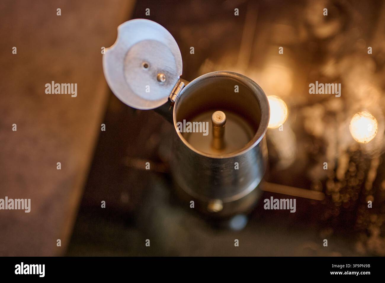 Vista dall'alto di una macchina da caffè a moka argentata vuota aperta appoggiata su un fornello. Foto Stock