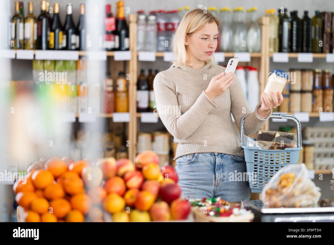 L'acquirente donna verifica l'idoneità - scansiona il codice QR sul barattolo dell'etichetta maionese nel negozio di alimentari Foto Stock