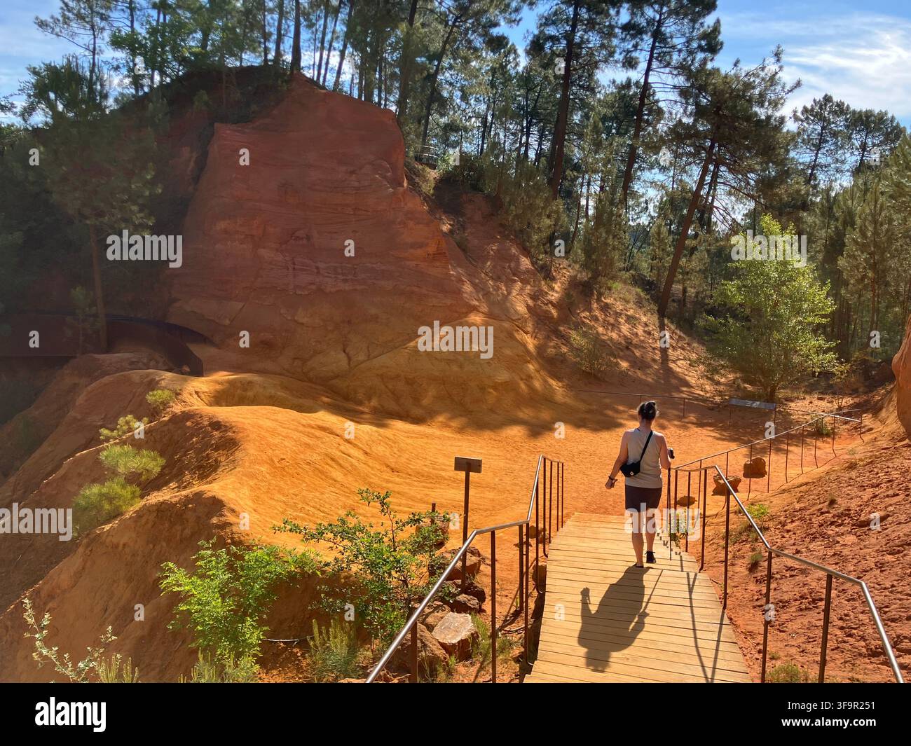 Un visitatore scende una scala di legno lungo il Sentier des Ocres tra le scogliere di ocra rossa a Roussillon, Luberon, Francia. - Immagine stock catturata con smartphone