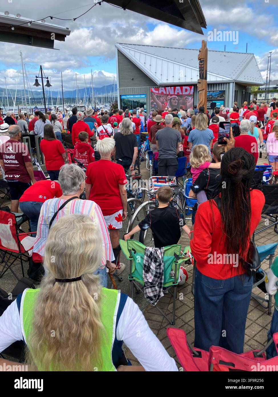 La folla si raduna in rosso al Comox Marina Park per guardare una partita di calcio canadese trasmessa durante i mondiali di calcio FIFA del 2026. Foto Stock
