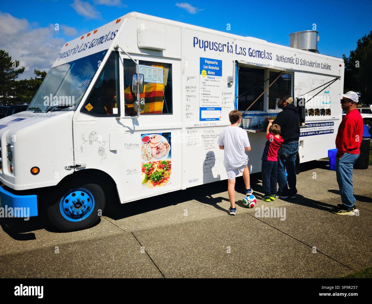 I clienti ordinano cibo al food truck Pupuseria Las Gemelas che serve cucina salvadoregna all'aperto in una giornata soleggiata a Comox, nella British Columbia. - Immagine stock catturata con smartphone