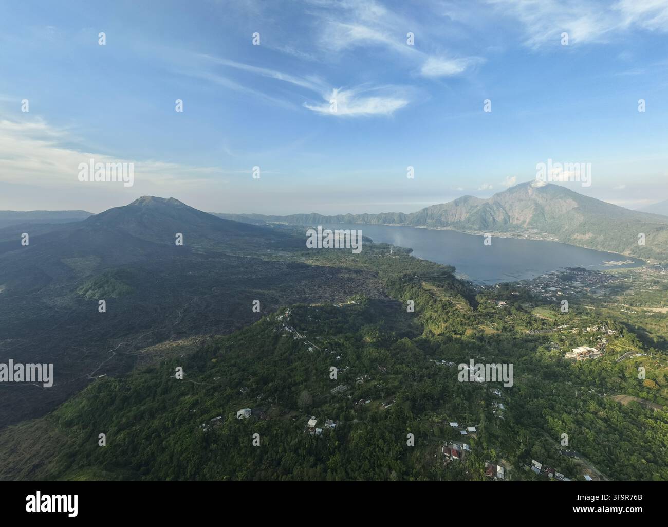 Vista aerea del Monte Batur e del Monte Abang che si affacciano sul sereno Lago Batur, circondati da un paesaggio vulcanico lussureggiante e da piccoli villaggi a Kintam Foto Stock