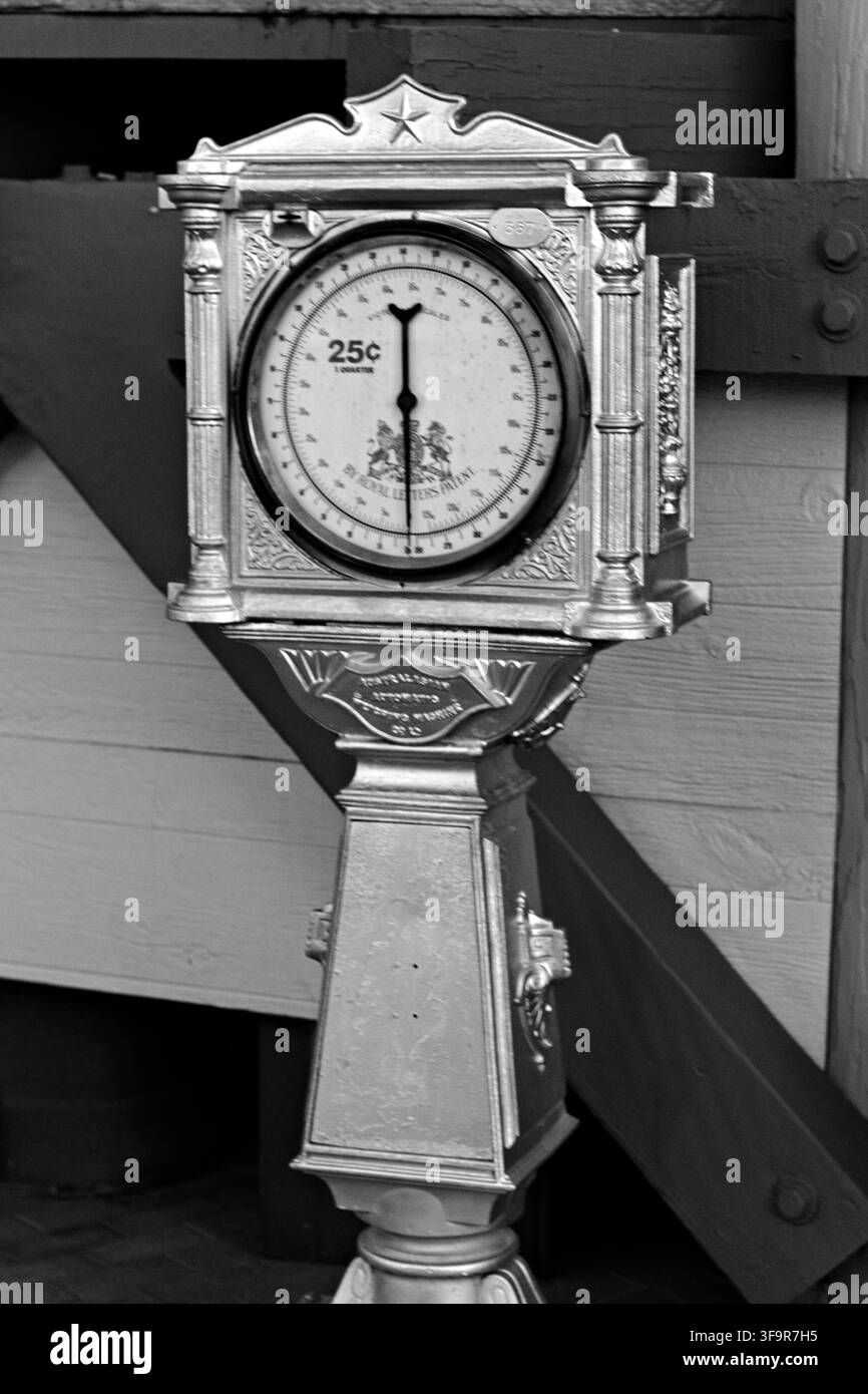 Bilancia vintage in argento si staglia contro un muro di legno. Il quadrante simile a un orologio mostra il prezzo '25c'. Lavorazione metallica ornata con design classico. Perfetto per retro, vintage, Foto Stock