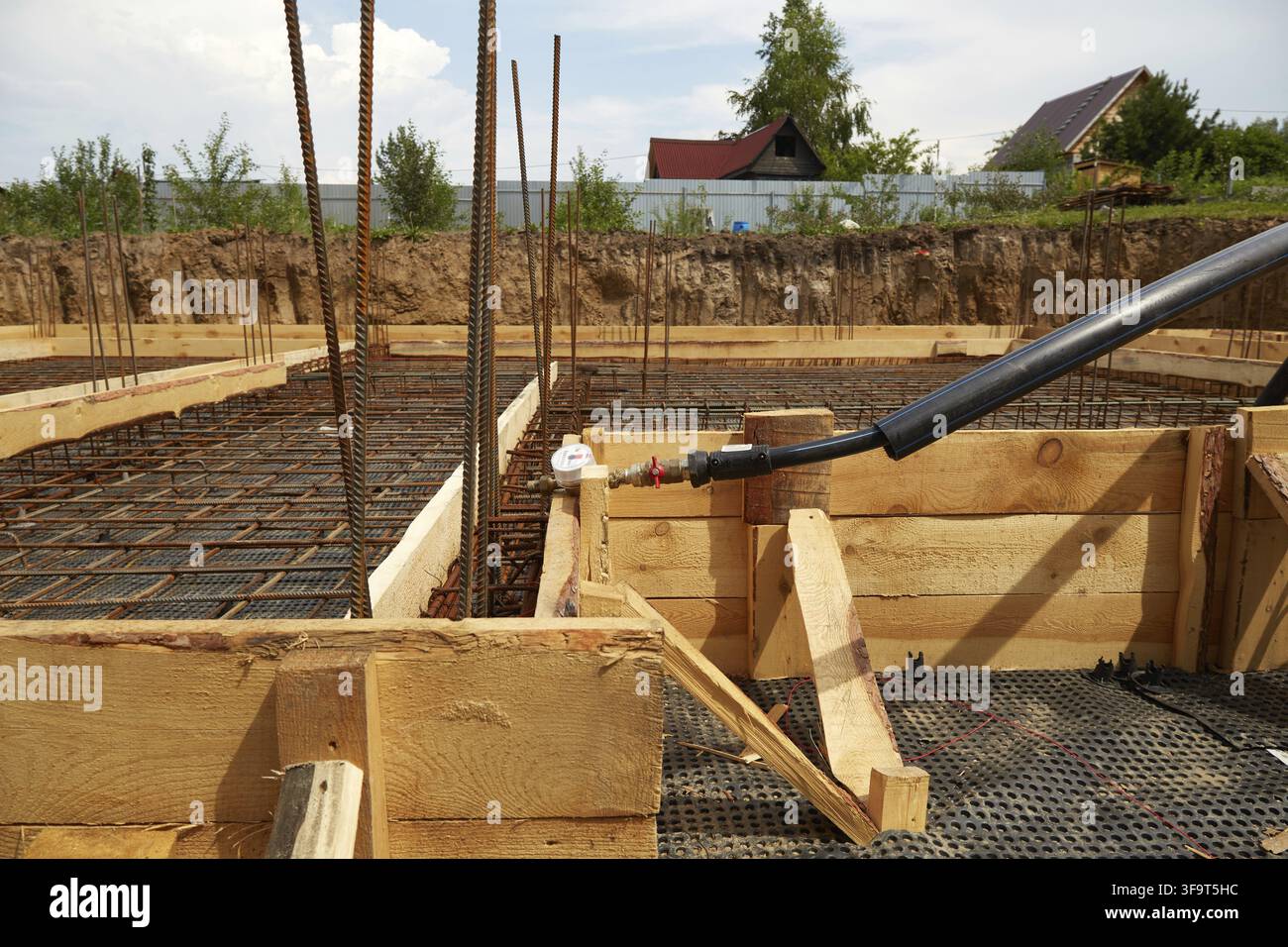 La costruzione di una fondazione in cemento utilizzando acciaio di rinforzo preparato in cantiere. Le armature in acciaio vengono posate in stampi di legno e il Foto Stock