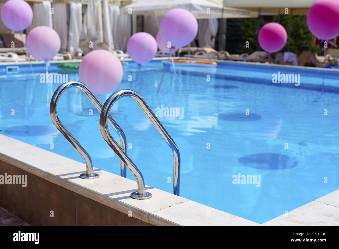 Piscina con acqua blu e palline colorate alla luce del sole Foto Stock