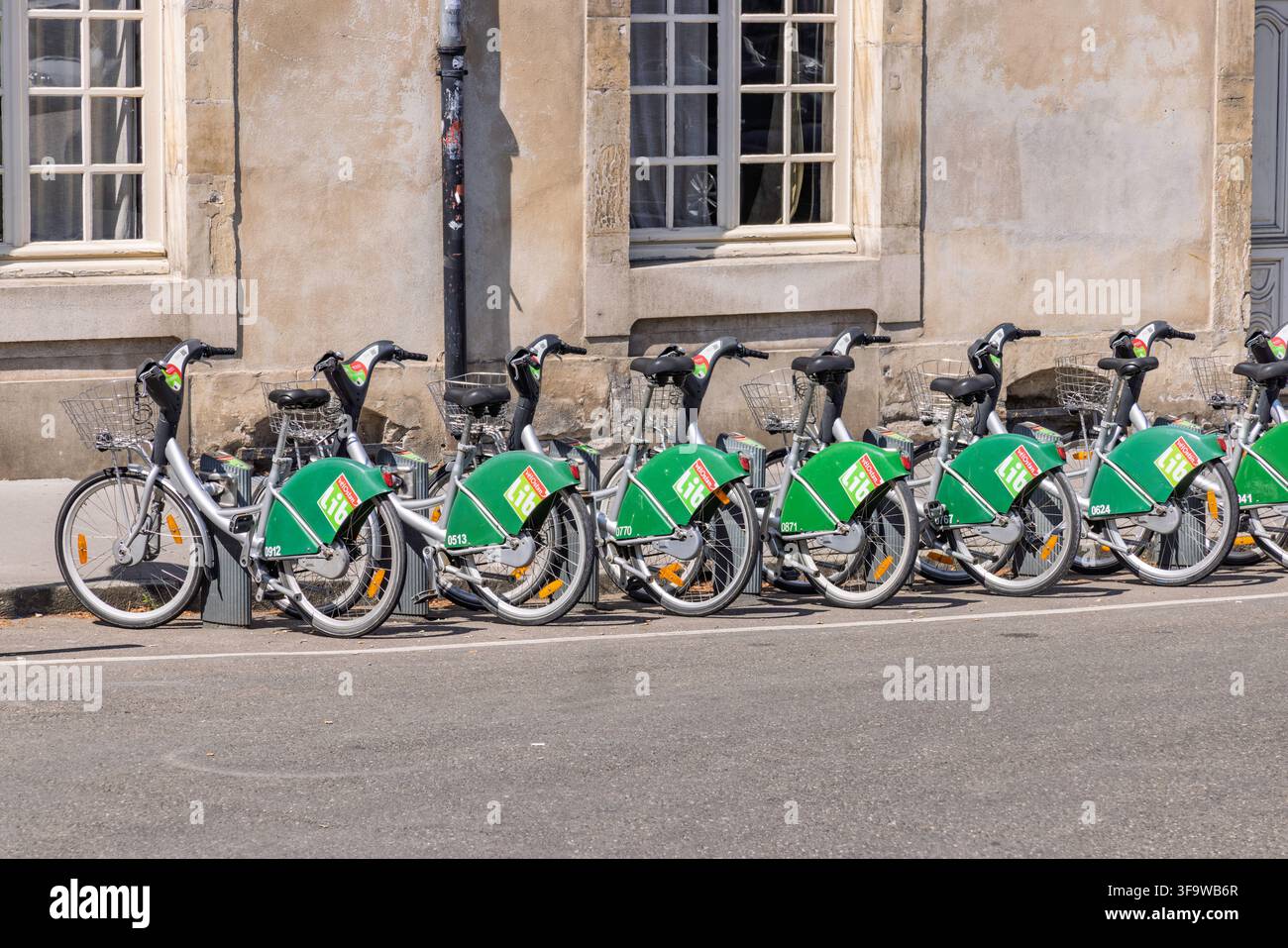Nancy, Francia, 2 agosto 2026. Fila di biciclette verdi Vélostan'lib a noleggio pubblico parcheggiate in una stazione di bike sharing lungo la strada. Foto Stock